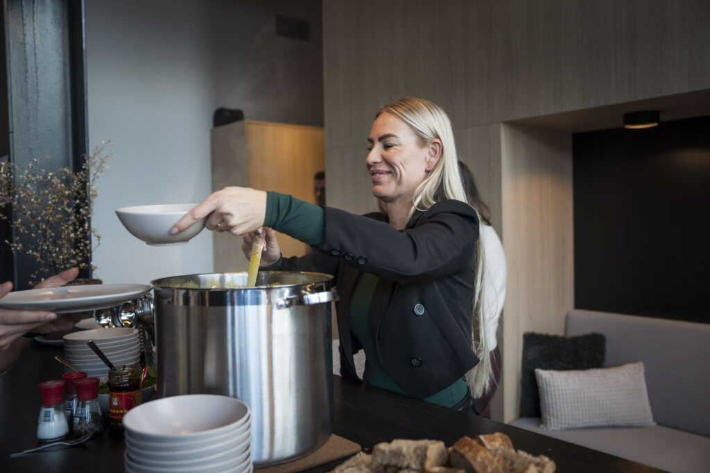 Gastvrouw die een kopje vers gemaakte soep uitdeelt.